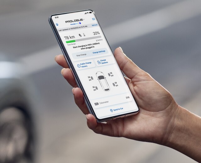 Hand holding a device opened to the HondaLink app with Honda vehicle in background. 