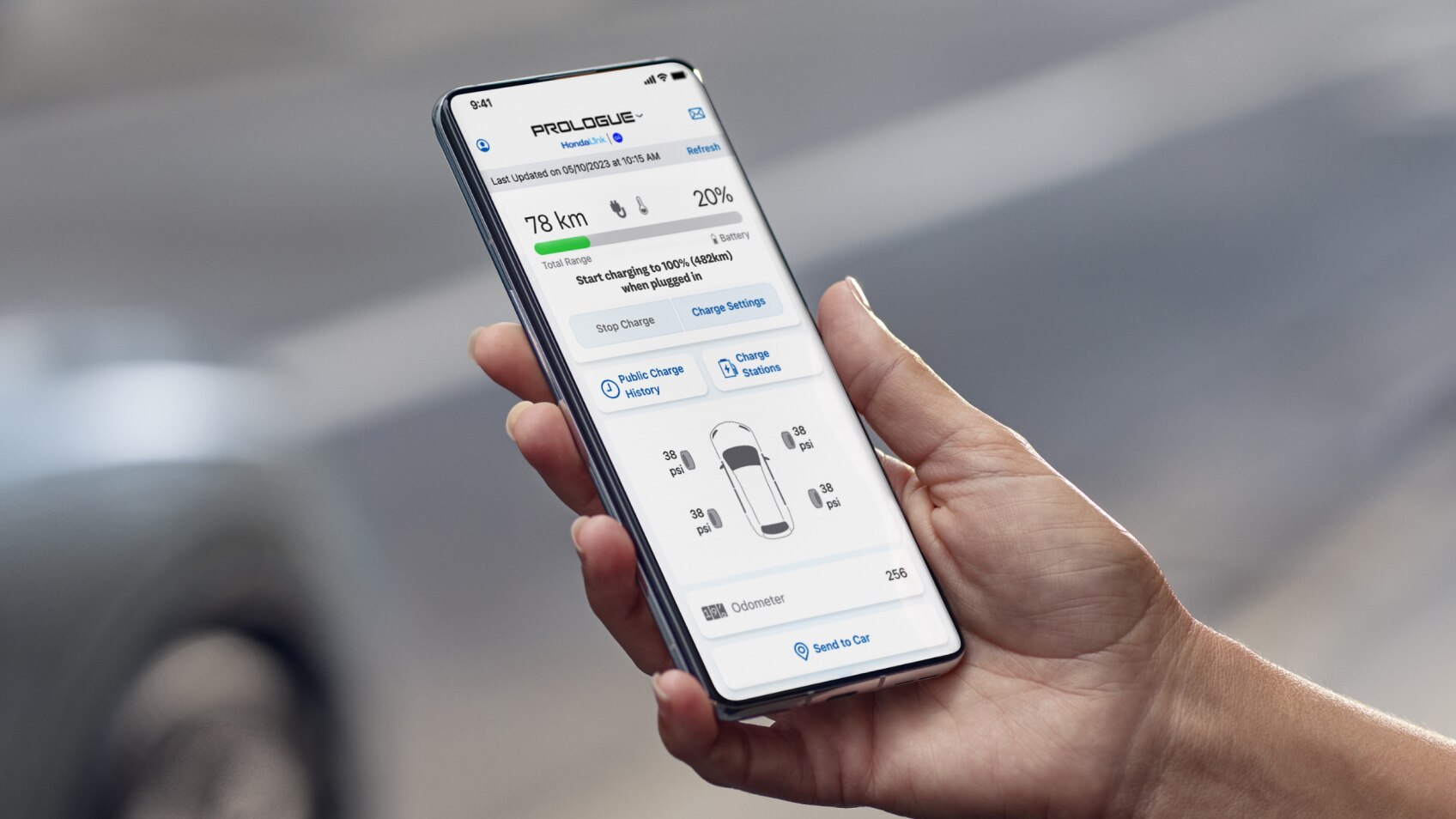 Hand holding a device opened to the HondaLink app with Honda vehicle in background. 