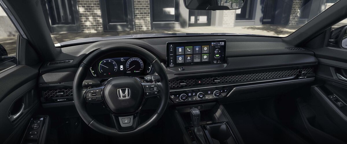 Panoramic wide view of steering wheel and dashboard. Trendy condo building can be seen through the windshield.