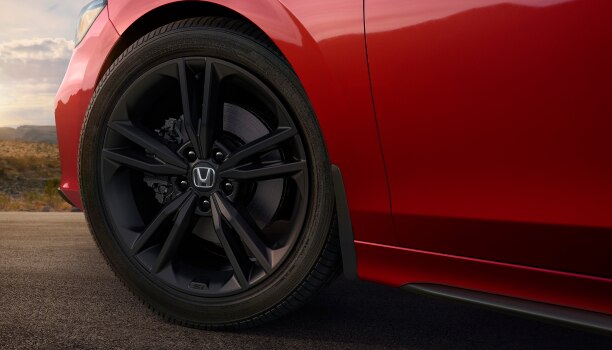 Gros plan de la roue noire d’une Civic Si rouge.