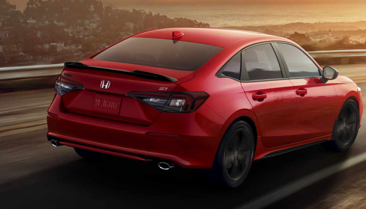 Gros plan 3/4 arrière de la Civic Si rouge roulant sur l’autoroute, mettant en valeur l’aileron arrière.