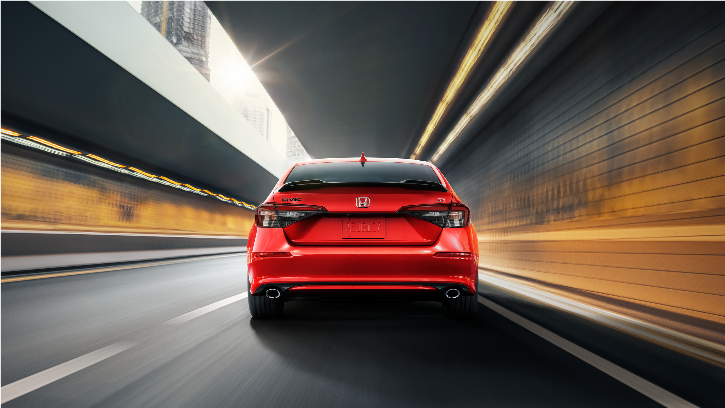 Vue arrière d’une Civic Si rouge roulant dans un tunnel.