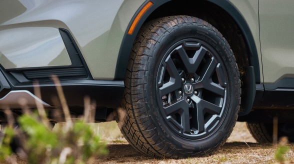 Closeup view of the front of a green CR-V, highlighting its black aluminum-alloy wheel.