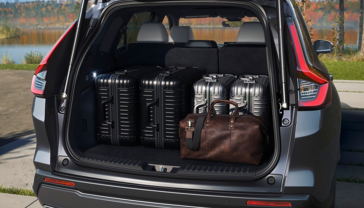 Rear view of open tailgate on a parked CR-V filled with luggage; lake and fall-coloured trees as backdrop. 