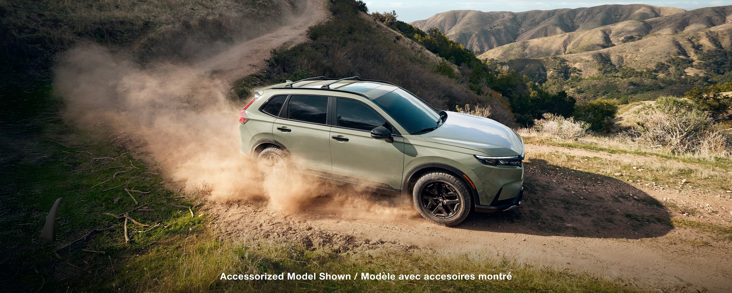 Wide, long shot of Gren CR-V kicking up dust in the desert. 