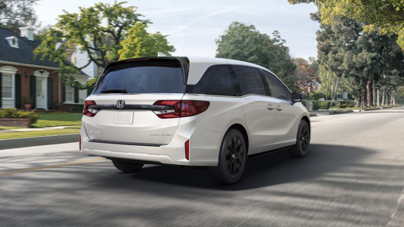 3/4 rear view of white Odyssey braking in suburban street.