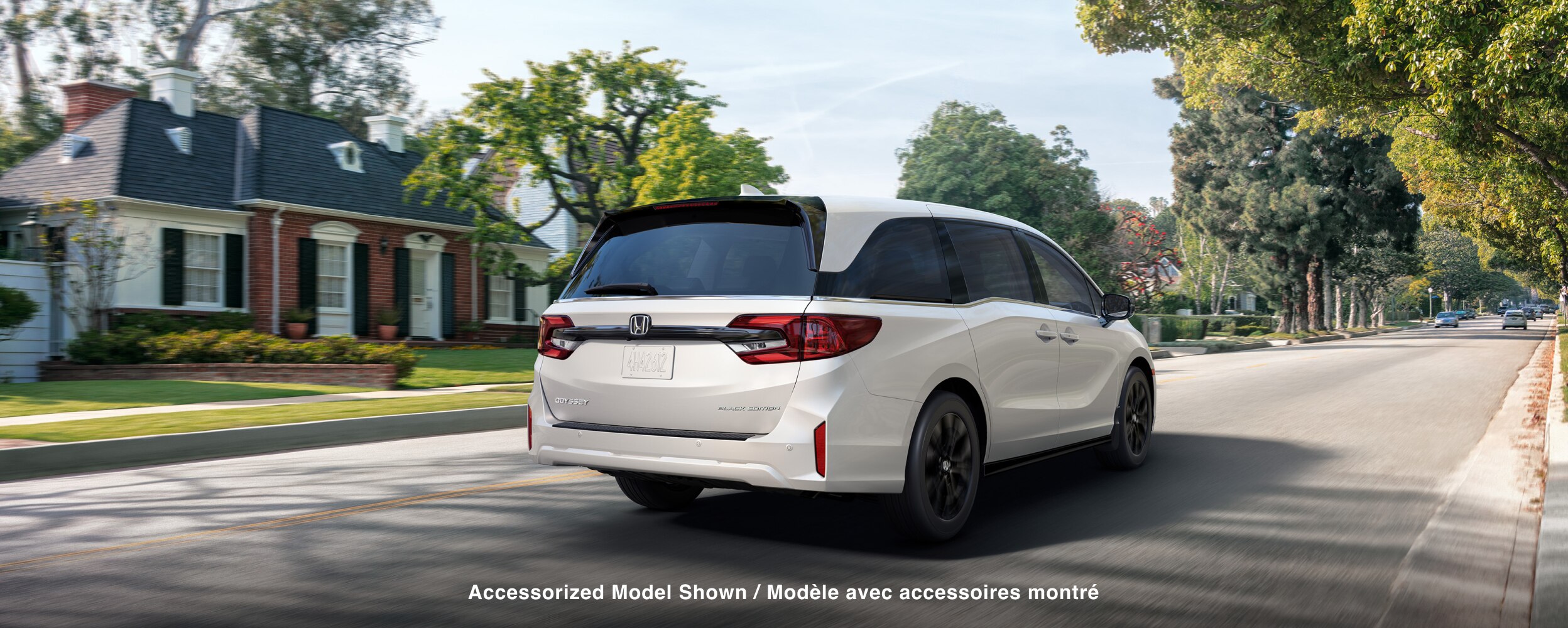 3/4 rear view of white Odyssey braking in suburban street.