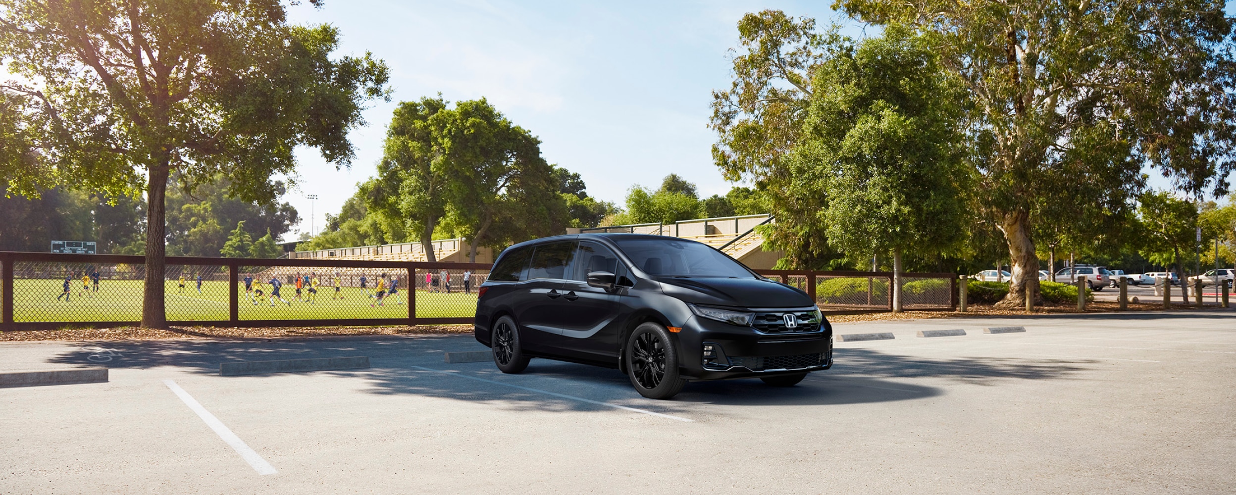 3/4 front view of black Odyssey parked by a soccer field.