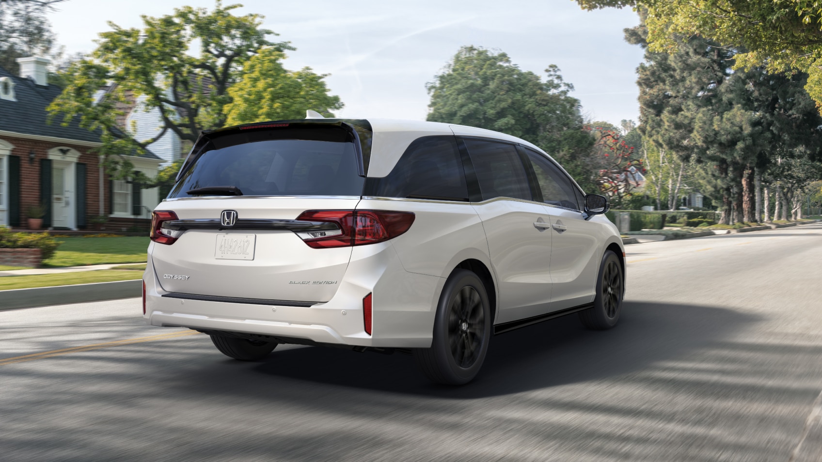 3/4 rear view of white Odyssey braking in suburban street.