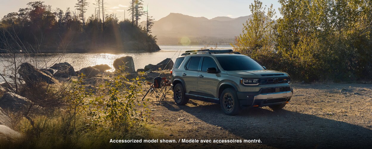 A grey Passport is parked in front of a lake. 