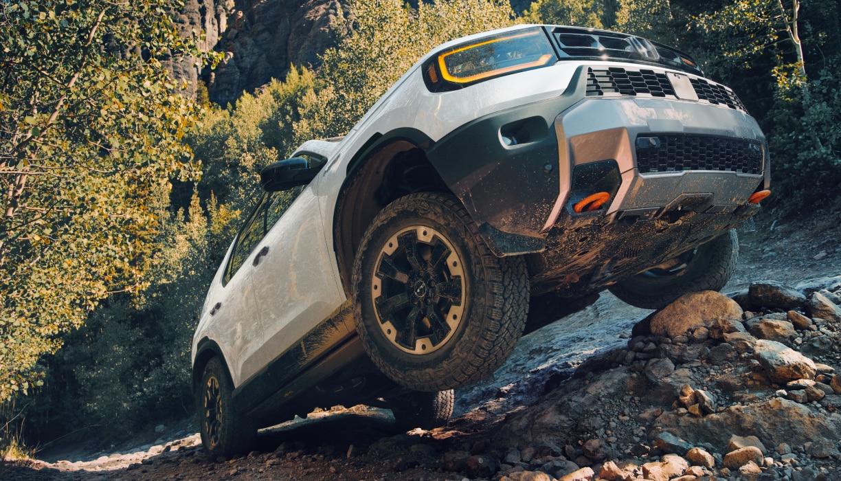A white Passport drives over rough mountain terrain.