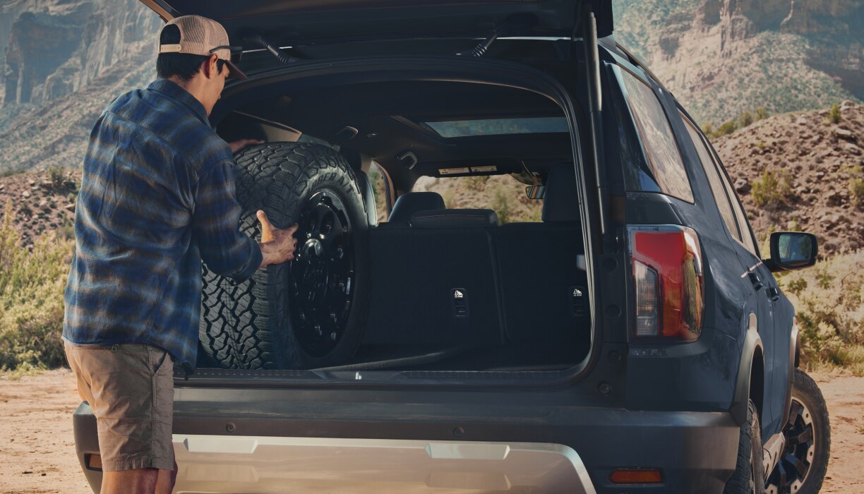 Rearview shot of a man placing items in the back of a Passport. 