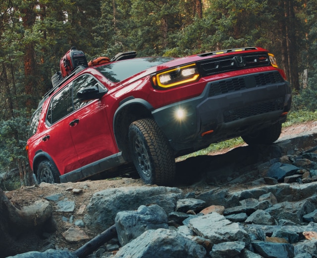 A red Passport driving on rough mountain terrain.