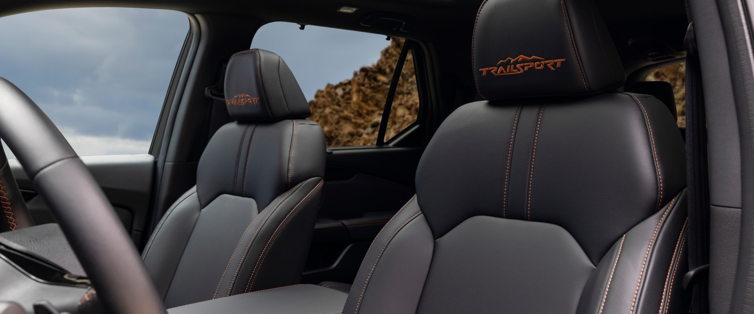 Vue intérieure des sièges avant du Pilot Trailsport, avec la mention "Trailsport" en surpiqûres orange.