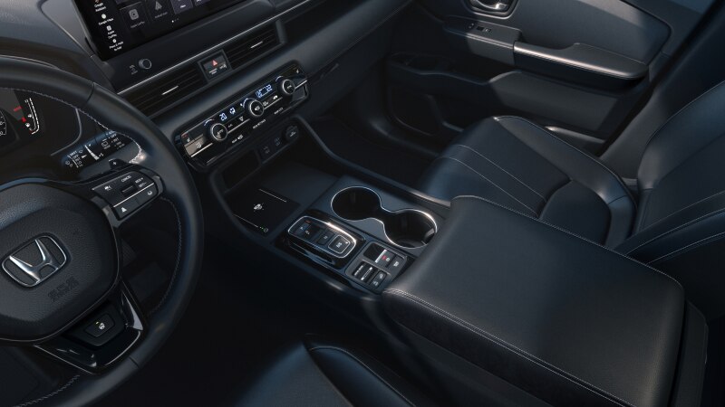 Driver’s side view of the steering wheel, dashboard, centre console and cup holders.