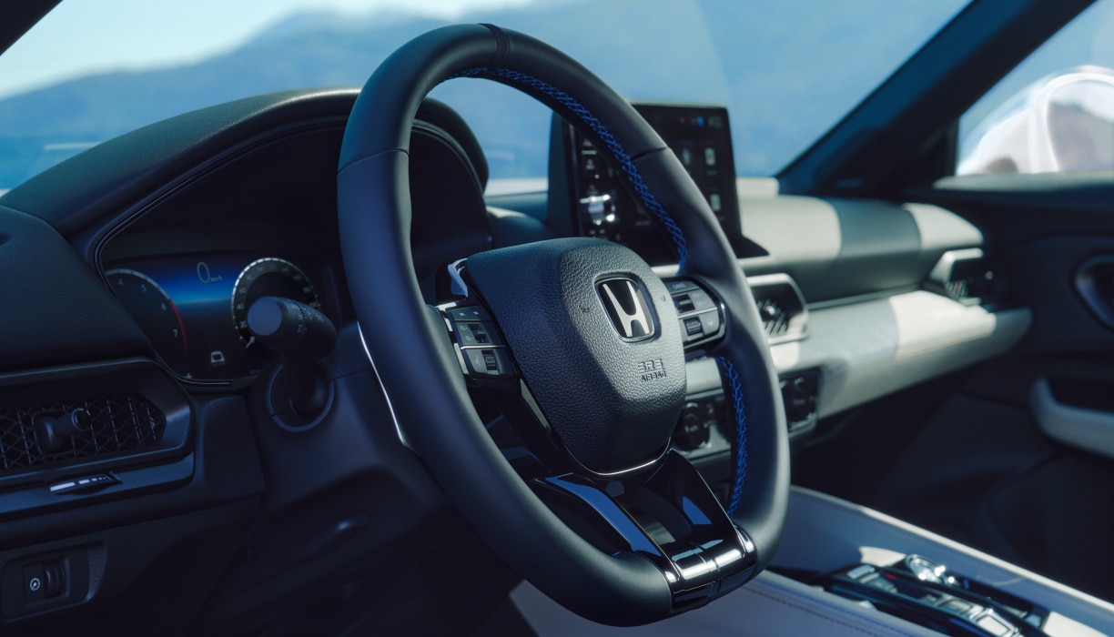 Vue latérale du volant. La console centrale, le tableau de bord et l’écran tactile sont visibles à l’arrière-plan.
