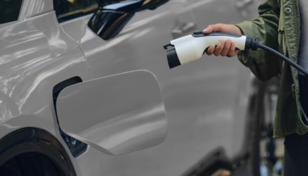 Gros plan d’un propriétaire de Prologue qui recharge le véhicule à une borne de recharge électrique.