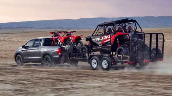 Un Ridgeline tire une remorque transportant des motocross dans le désert.