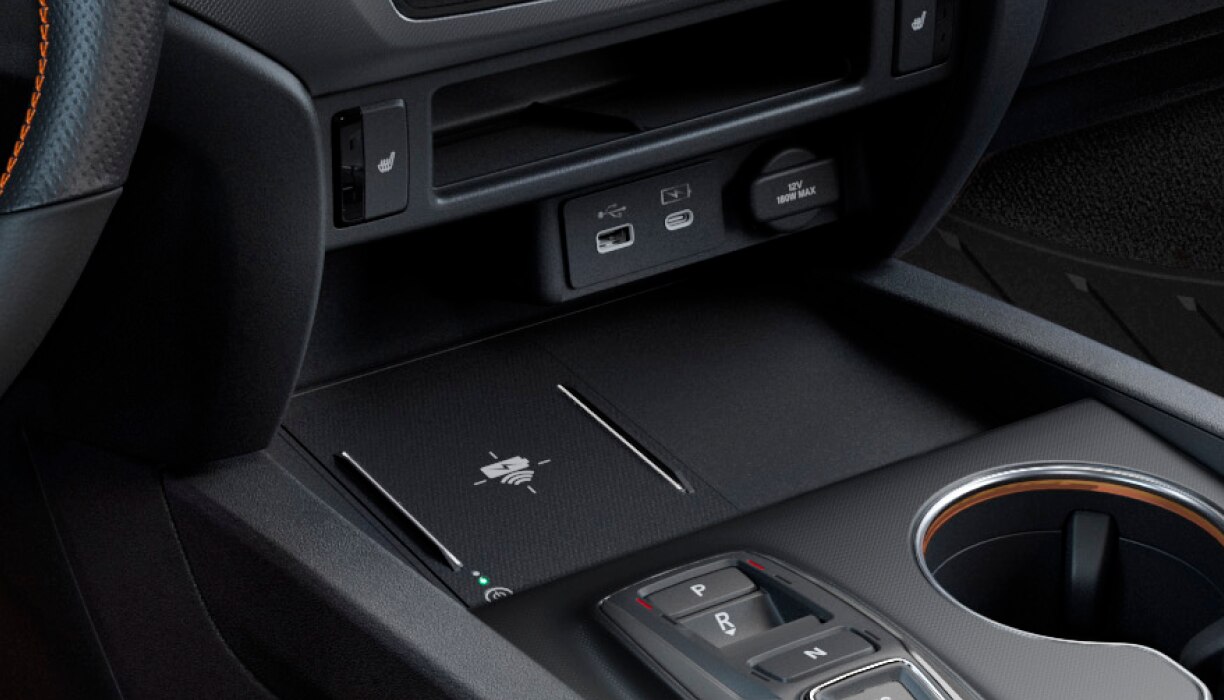 Gros plan sur les ports de recharge USB et le socle de recharge sans fil dans la console centrale.