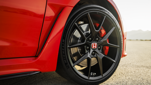 Gros plan d’une roue avant à bordure noire d’une Type R rouge dans le désert.