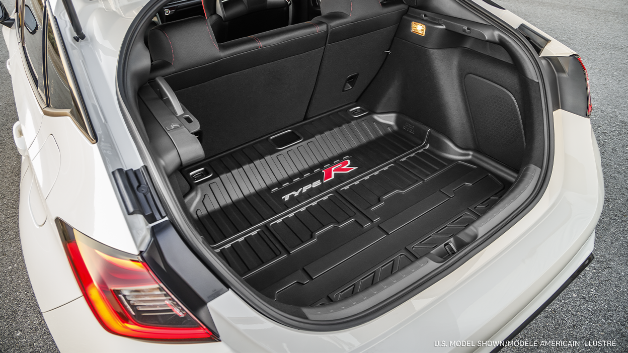 Gros plan du coffre ouvert d’une Type R blanche montrant les haut-parleurs et le tapis de coffre en caoutchouc marqué « Type R ».