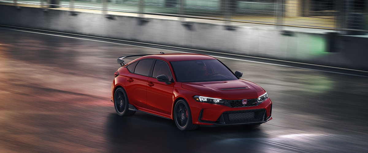 Vue aérienne de trois quarts d’une Type R rouge conduite sur un circuit de course la nuit.