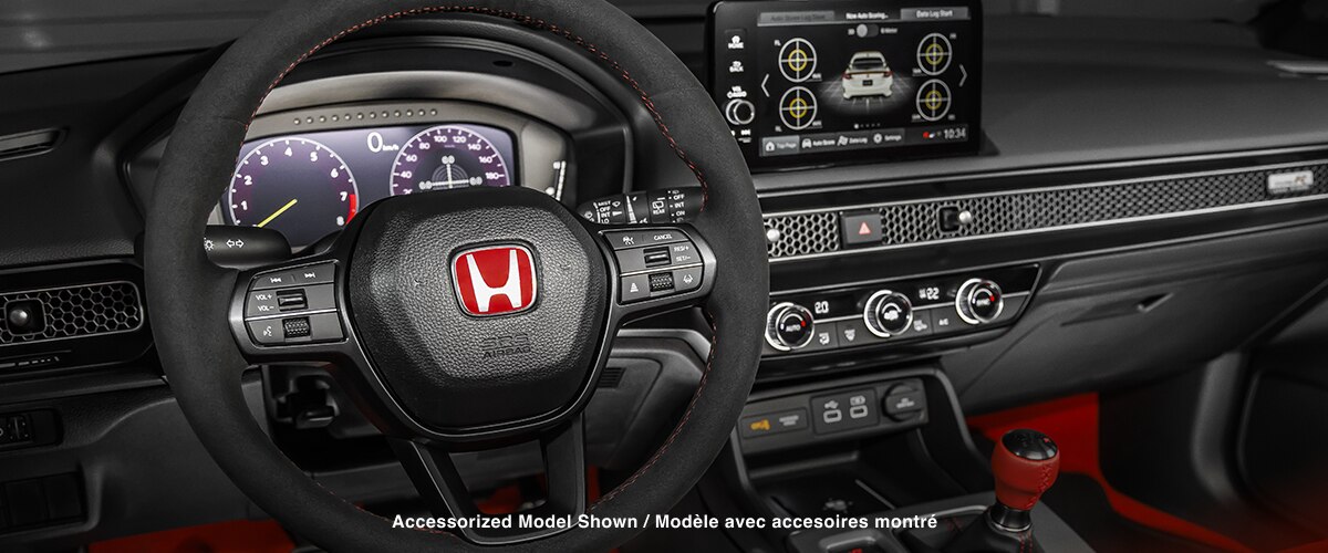 Medium closeup of steering wheel, dashboard, centre console, and gear shifter.