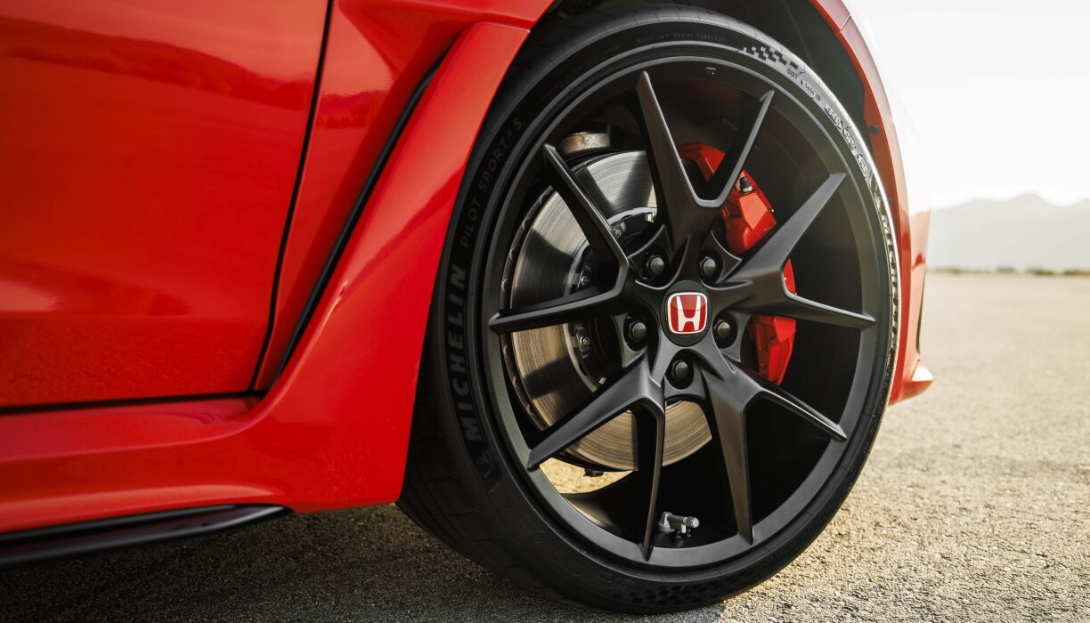 Closeup of black rimmed front wheel on a red Type R in the desert.