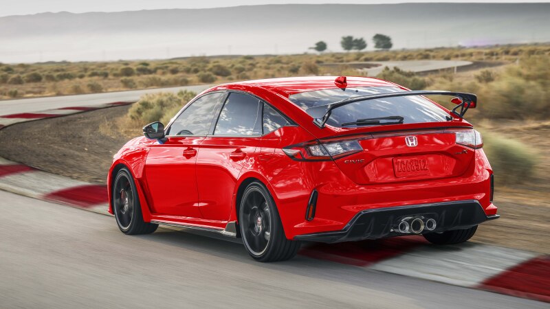 3/4 rear view of red Type R taking a turn on track.