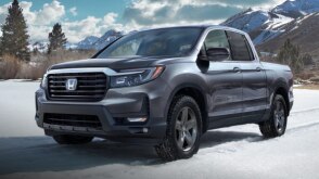 3/4 front view of grey Ridgeline in the snowy outdoors.