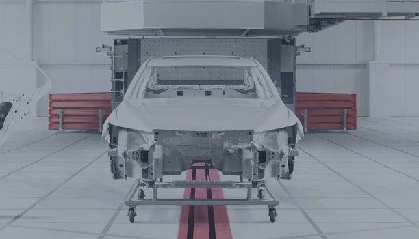 Le châssis d’un véhicule Honda posé sur un élévateur dans une salle blanche industrielle.